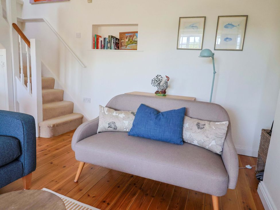 A living room with a sofa and bookshelf at Tithe Barn Cottage Litton Cheney near Burton Bradstock