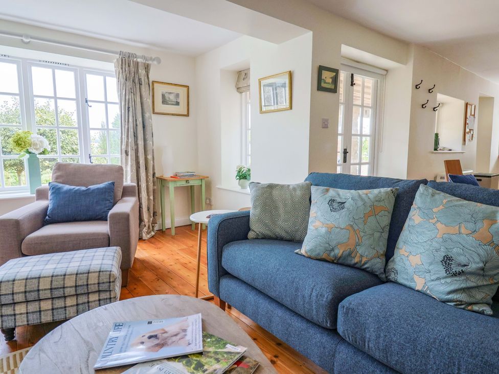 A living room with a sofa, armchair and coffee table at Tithe Barn Cottage in Litton Cheney near Burton Bradstock