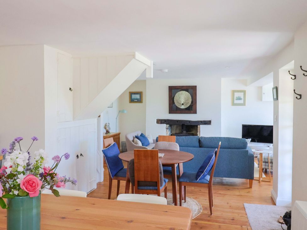 A living room with a sofa and a dining table at Tithe Barn Cottage in Litton Cheney near Burton Bradstock