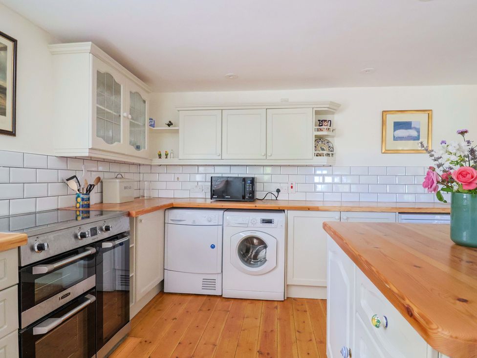 A kitchen with appliances and wooden countertop at Tithe Barn Cottage Litton Cheney near Burton Bradstock