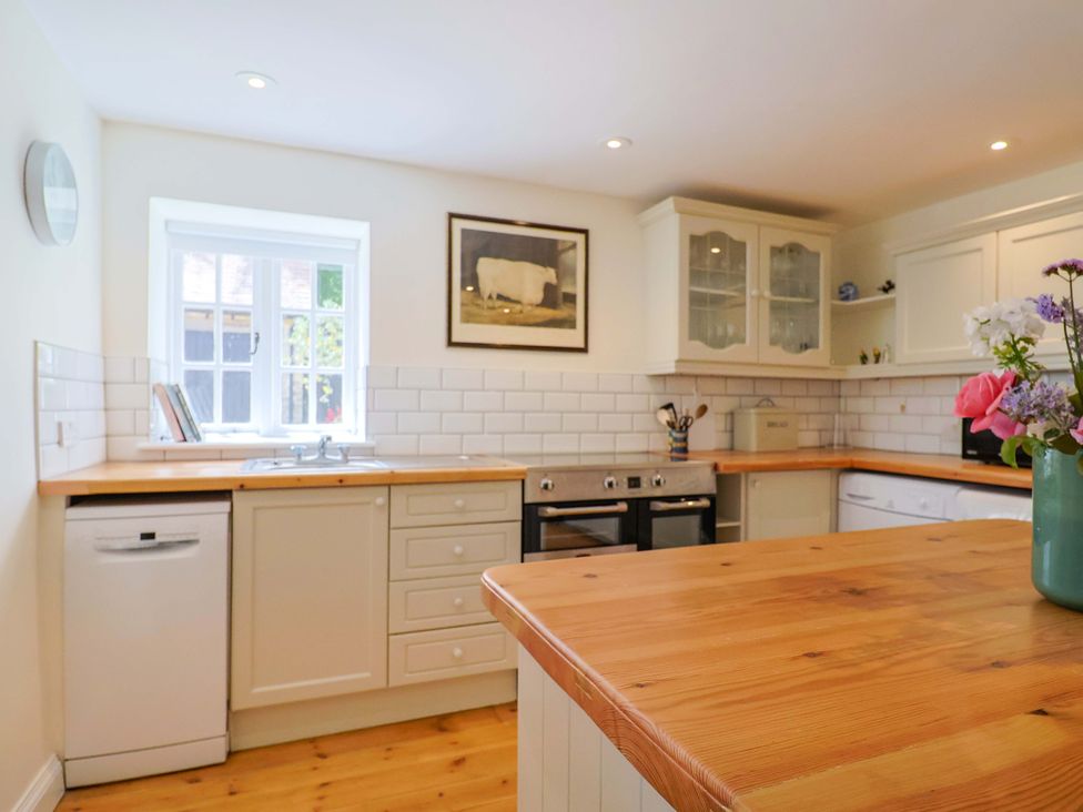 A kitchen with cabinets and a stove at Tithe Barn Cottage Litton Cheney near Burton Bradstock