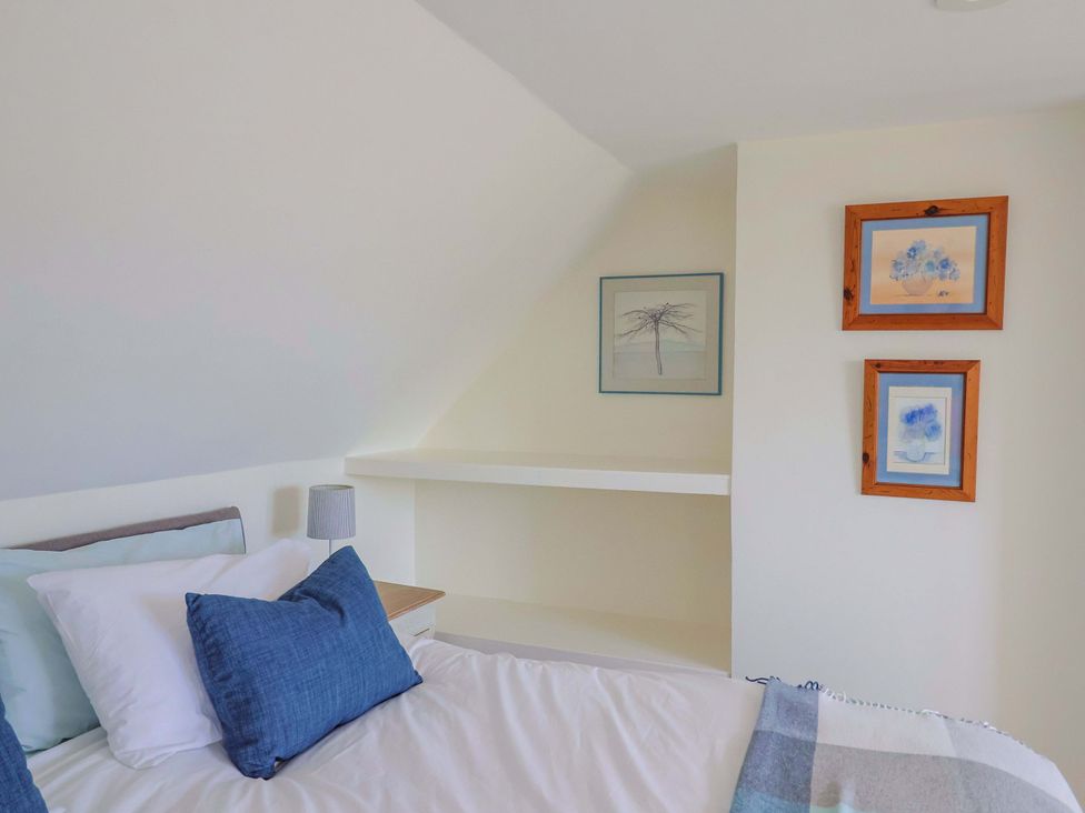 A bedroom with a bed and artwork at Tithe Barn Cottage in Litton Cheney near Burton Bradstock