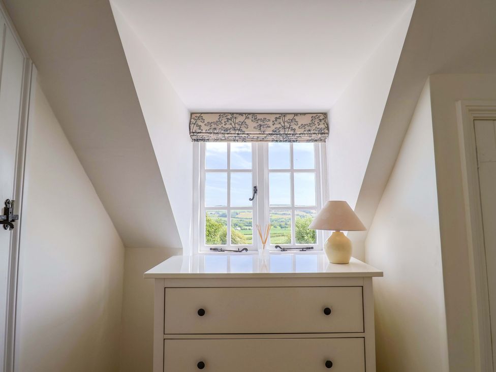A bedroom with a window and a lamp at Tithe Barn Cottage Litton Cheney near Burton Bradstock