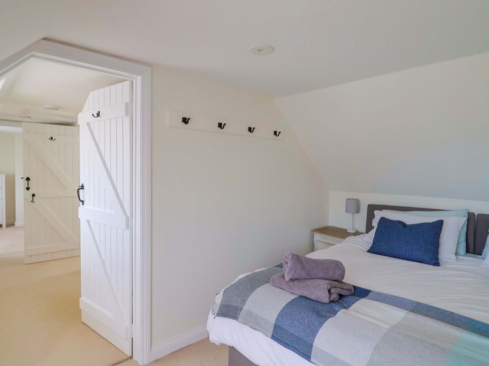 A bedroom with a bed and a side lamp at Tithe Barn Cottage in Litton Cheney near Burton Bradstock
