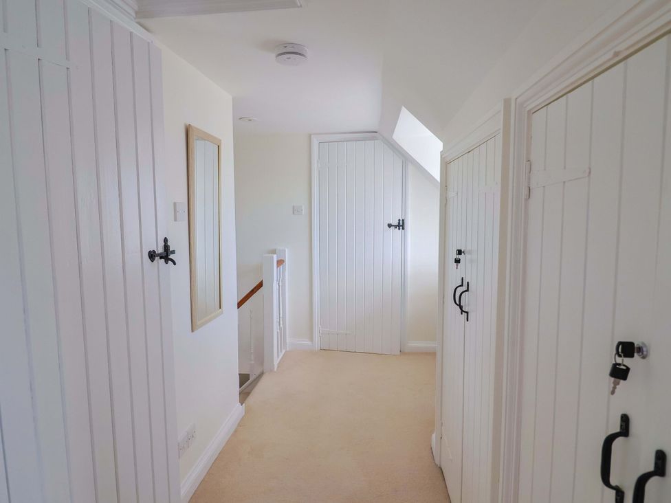A hallway with a mirror and doors at Tithe Barn Cottage Litton Cheney near Burton Bradstock
