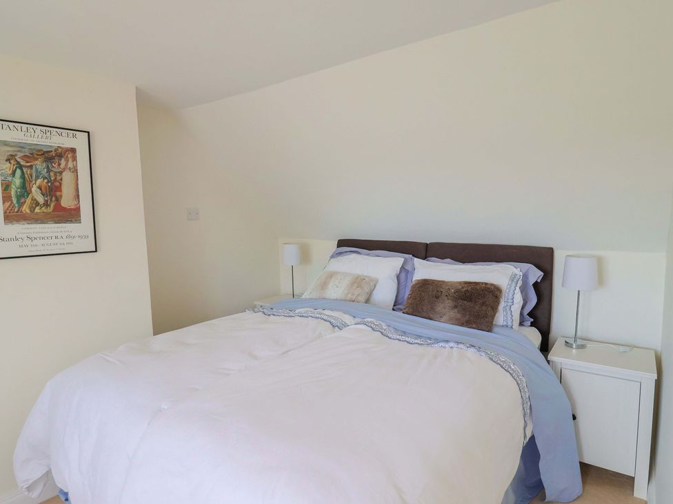 A bedroom with a bed and bedside table at Tithe Barn Cottage Litton Cheney near Burton Bradstock