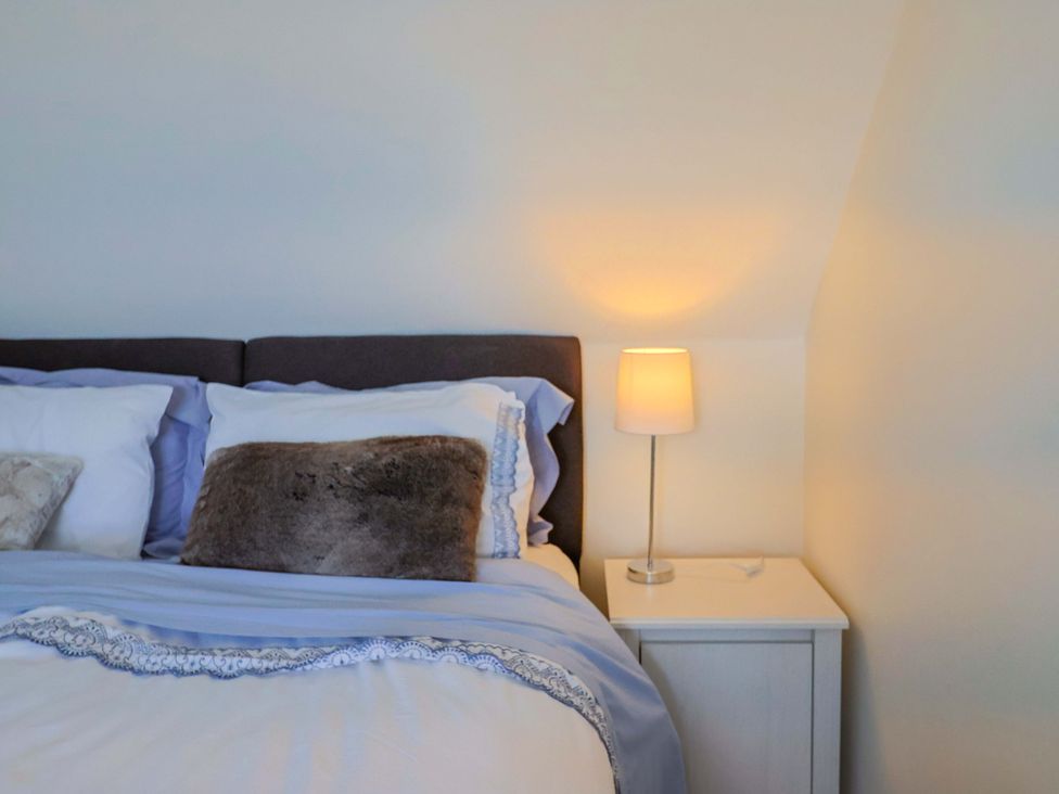 A bedroom with a bed and bedside table at Tithe Barn Cottage in Litton Cheney near Burton Bradstock