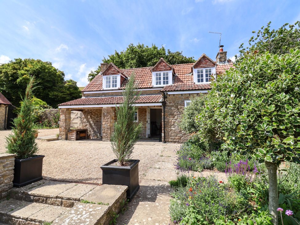 A house with a garden and gravel driveway at Tithe Barn Cottage in Litton Cheney near Burton Bradstock
