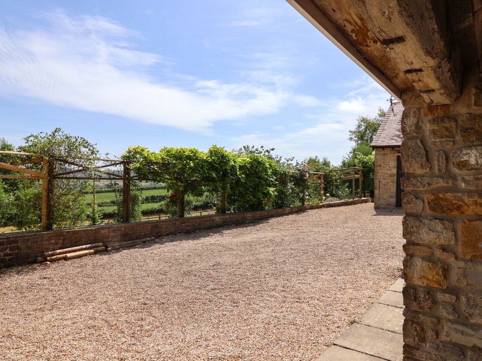 An outdoor area with gravel surface and stone wall at Tithe Barn Cottage in Litton Cheney near Burton Bradstock