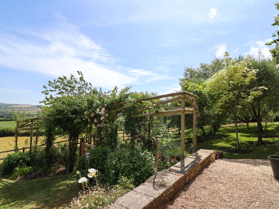 A garden with a trellis and flowers at Tithe Barn Cottage Litton Cheney near Burton Bradstock