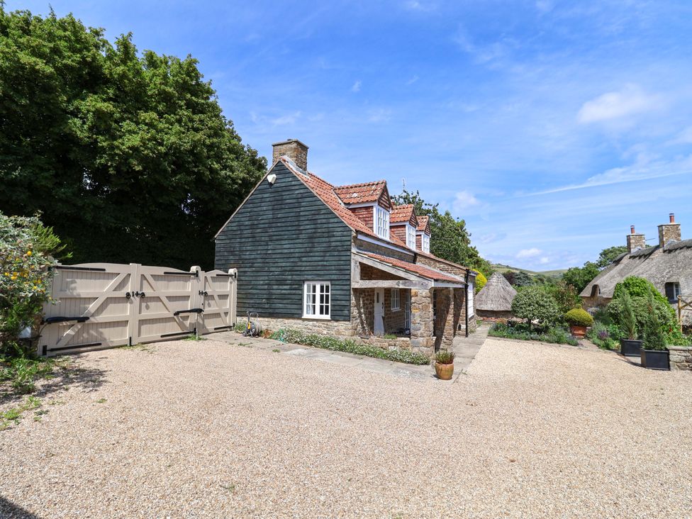 A house with a gravel driveway and gate at Tithe Barn Cottage in Litton Cheney near Burton Bradstock