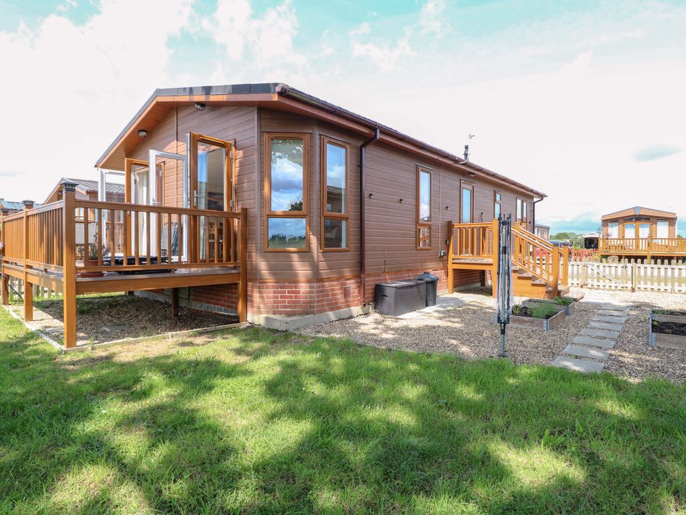 A lodge with a wooden deck and steps at Oak Tree Holiday Lodge in Stonham Aspal