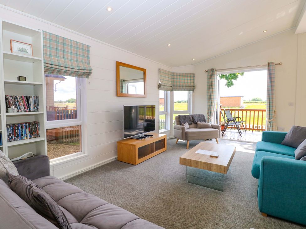 A living room with a television and sofa at Oak Tree Holiday Lodge in Stonham Aspal