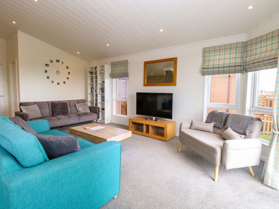 A living room with a sofa and television at Oak Tree Holiday Lodge in Stonham Aspal