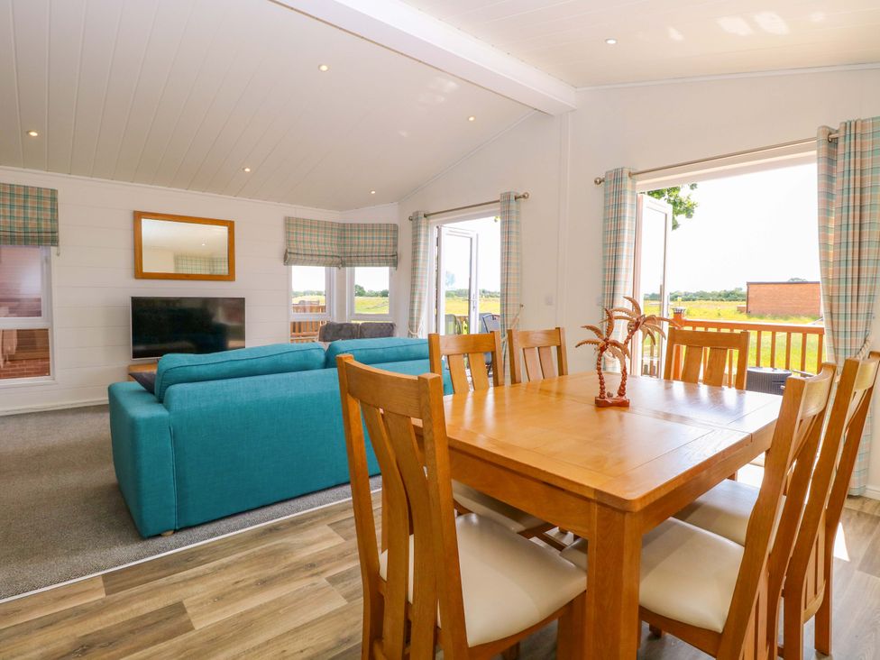 A living room with a sofa and dining table at Oak Tree Holiday Lodge in Stonham Aspal