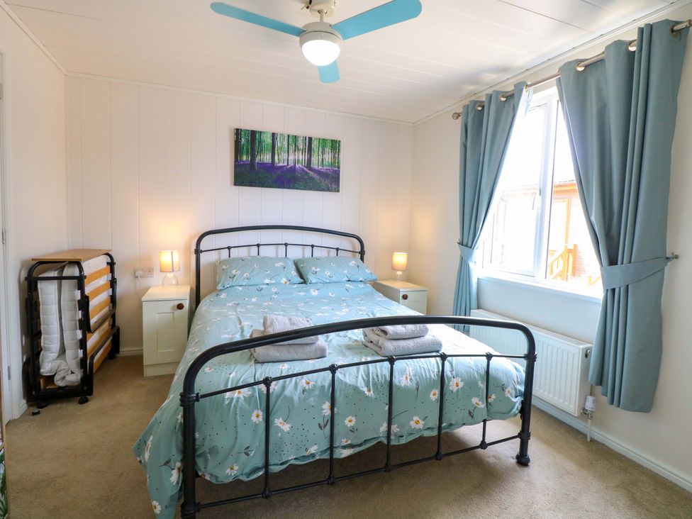 A bedroom with a double bed and bedside table at Oak Tree Holiday Lodge in Stonham Aspal
