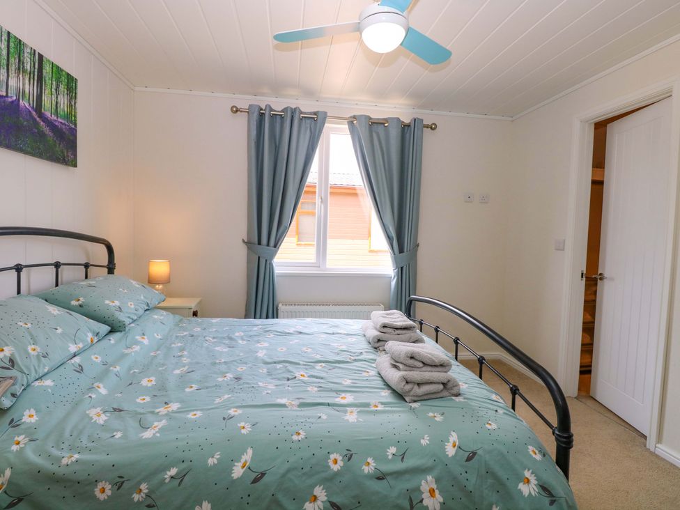 A bedroom with a bed and bedside lamp at Oak Tree Holiday Lodge in Stonham Aspal