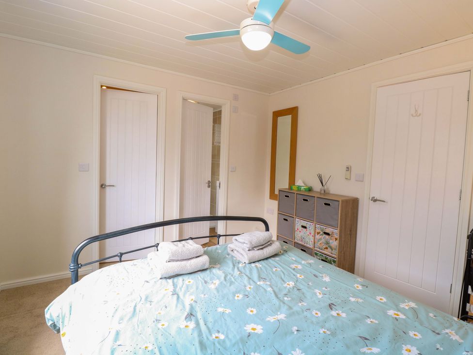 A bedroom with a bed and a cabinet at Oak Tree Holiday Lodge in Stonham Aspal