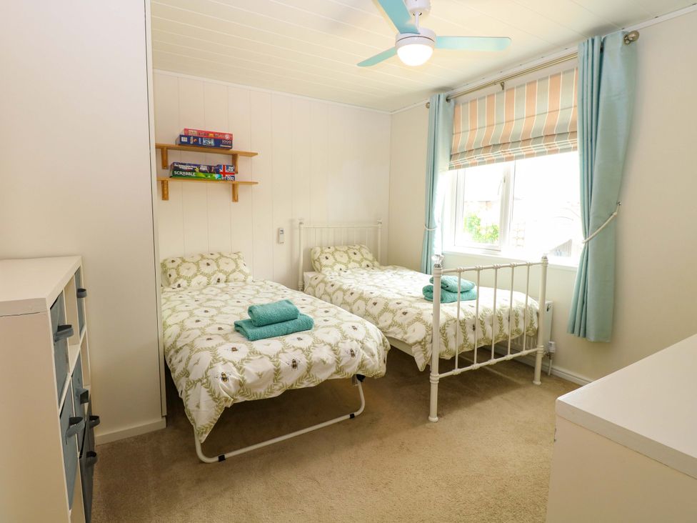 A bedroom with two beds and a shelf holding games at Oak Tree Holiday Lodge Stonham Aspal