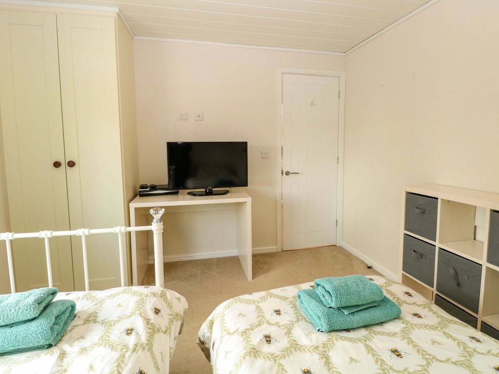 A bedroom with two beds and a television at Oak Tree Holiday Lodge Stonham Aspal