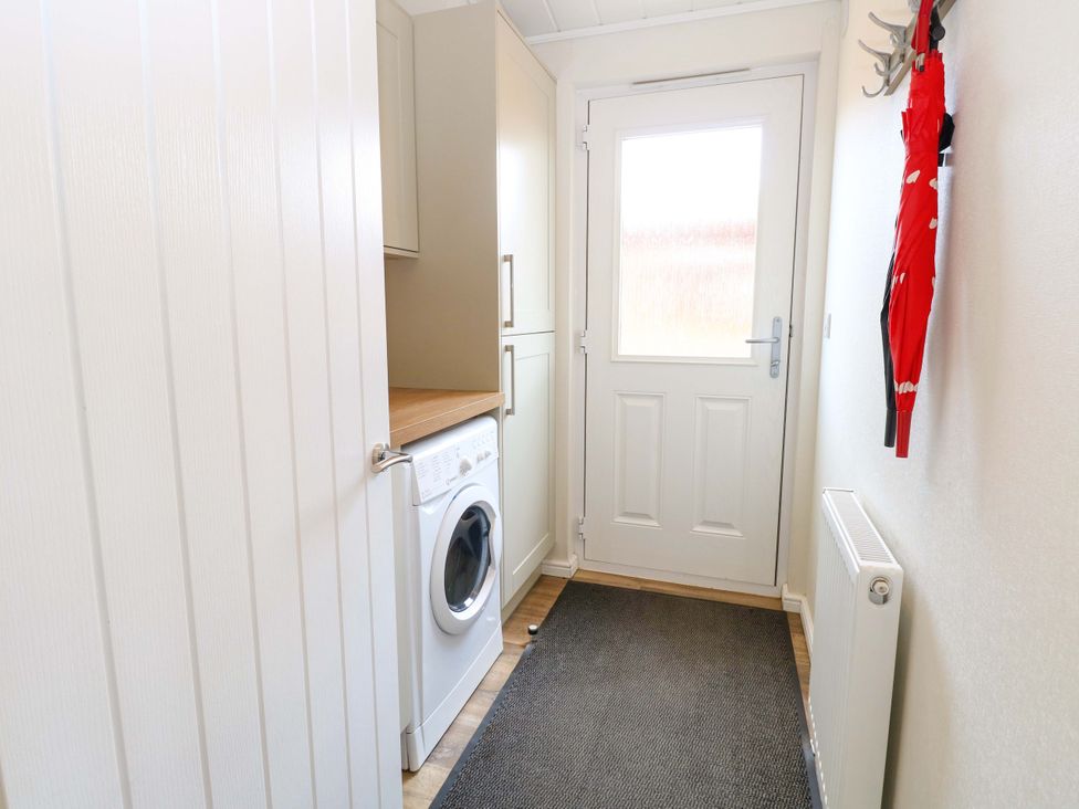 A utility room with a washing machine and a door at Oak Tree Holiday Lodge in Stonham Aspal