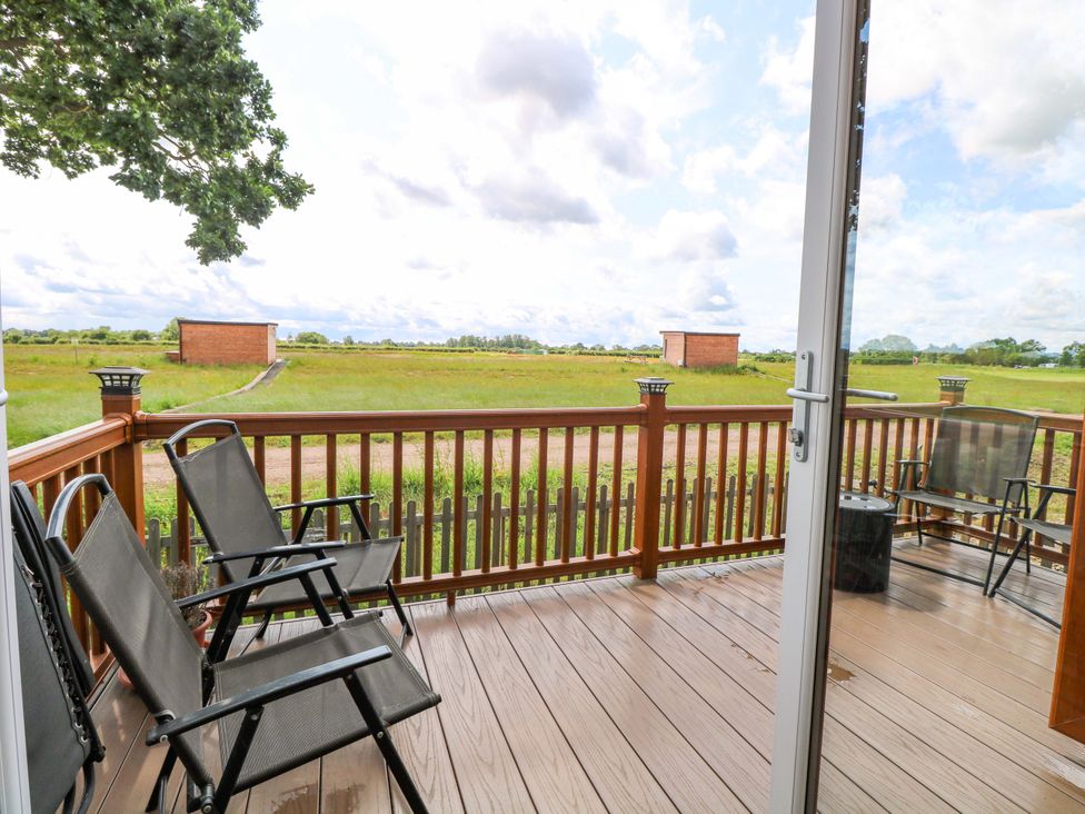 A deck with chairs and a view of the field at Oak Tree Holiday Lodge in Stonham Aspal