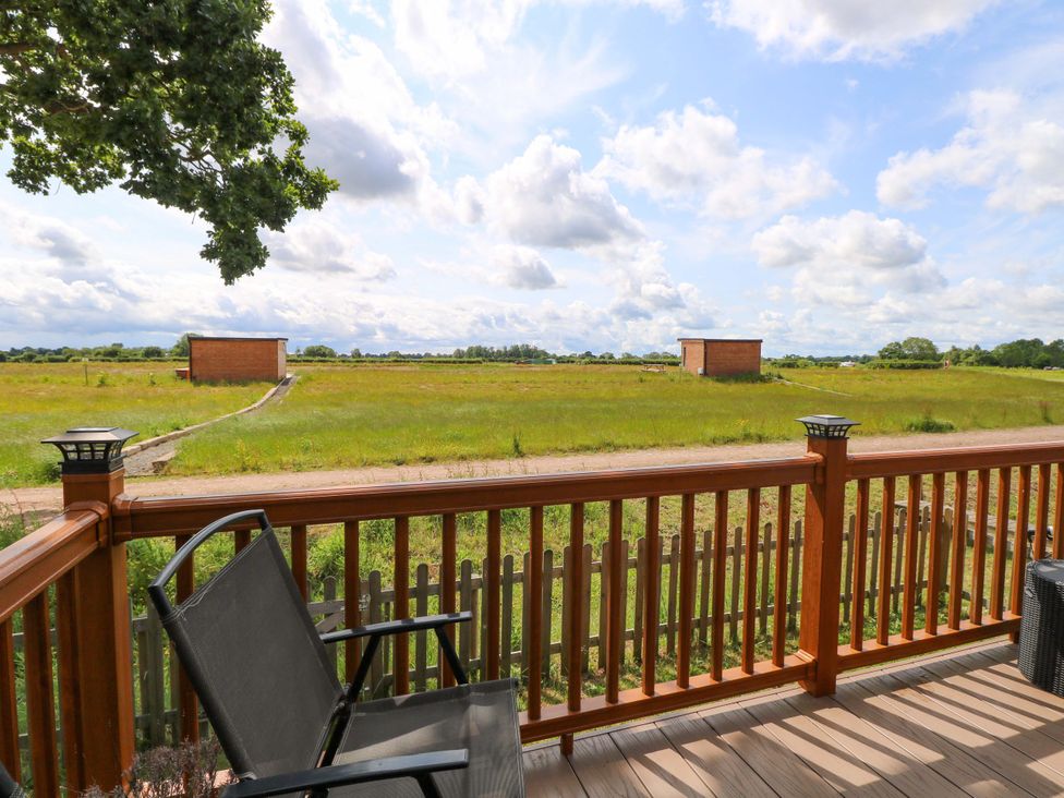 An outdoor view from a deck with a chair and grass at Oak Tree Holiday Lodge in Stonham Aspal