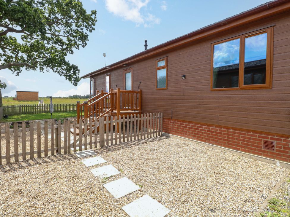 An outdoor area featuring a lodge with a wooden fence and steps at Oak Tree Holiday Lodge in Stonham Aspal