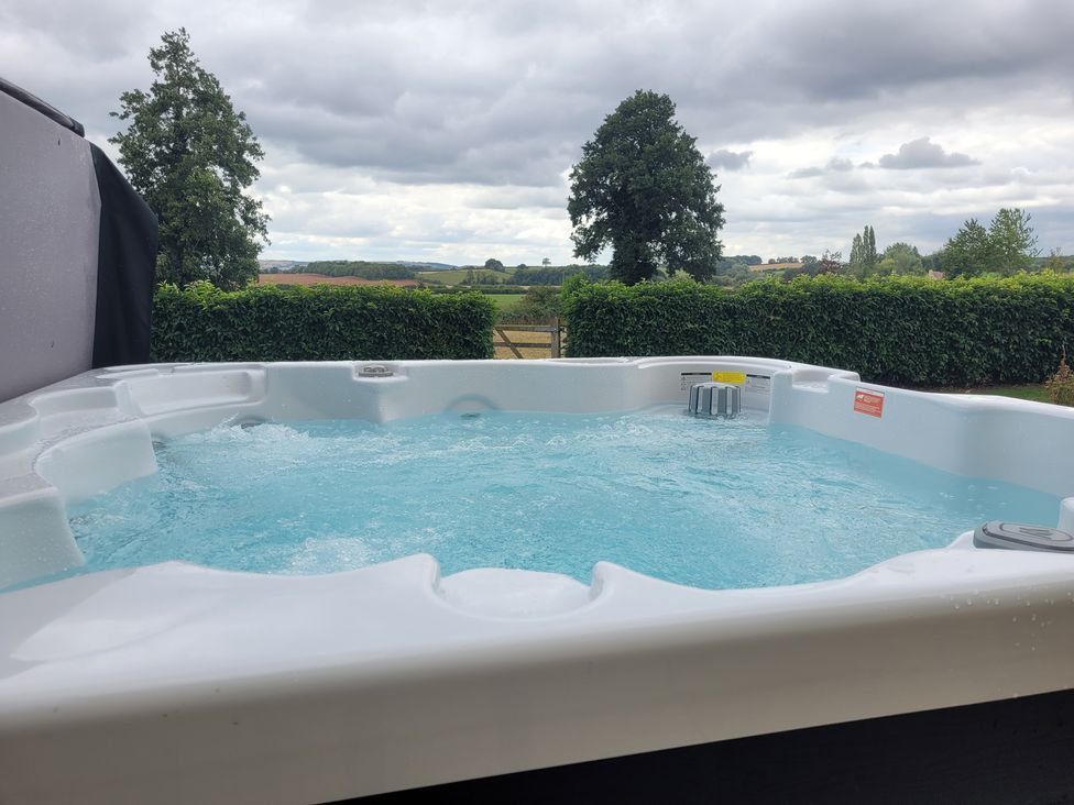A hot tub with water in an outdoor area at Filly Brook in Bishop's Frome