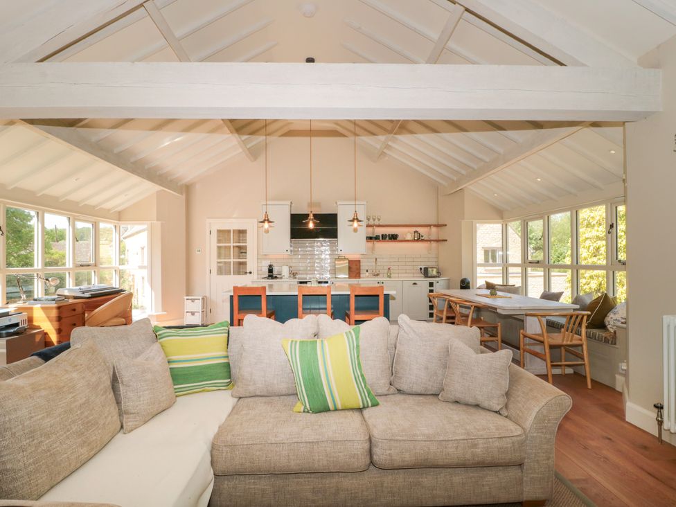 A living room with a sofa and kitchen area at Cleveley Mill in Enstone