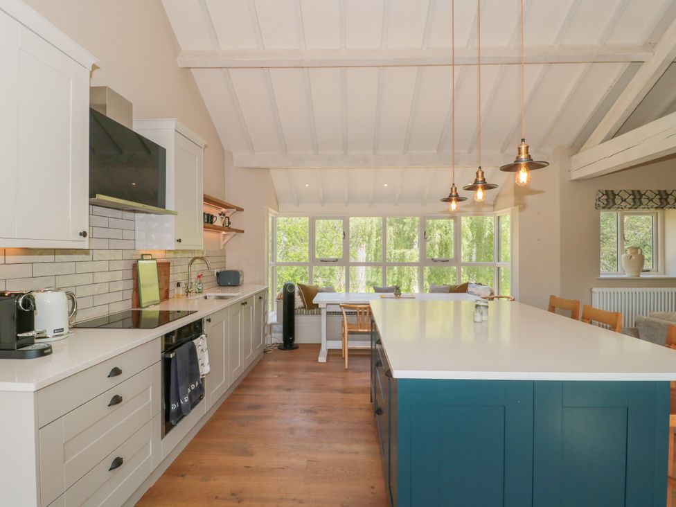 A kitchen with an island and stools at Cleveley Mill in Enstone