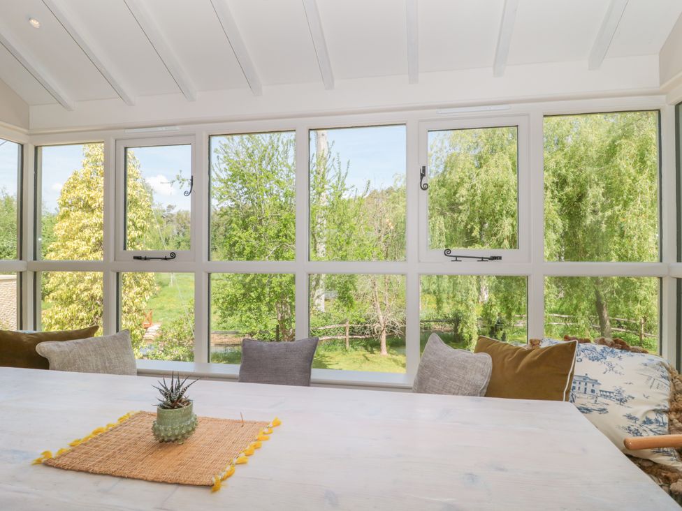A conservatory with a table and cushions at Cleveley Mill Enstone