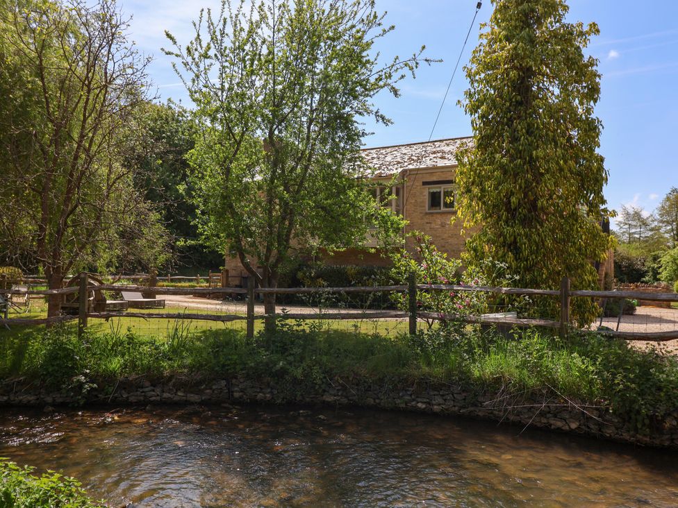 A house and trees by a stream at Cleveley Mill in Enstone