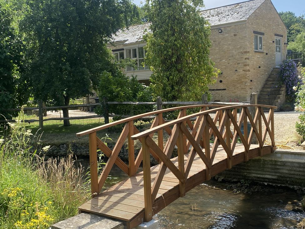 A wooden bridge over a stream near a building at The Annexe, Cleveley Mill in Enstone