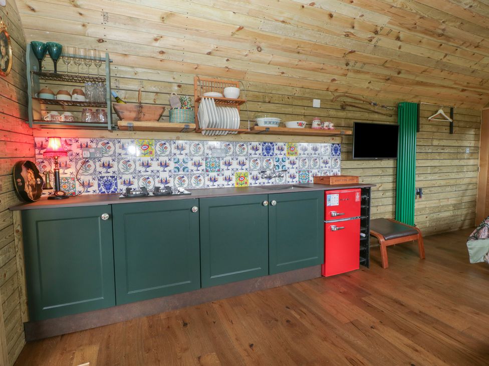 A kitchen with cabinets and a red refrigerator at Shepherd Hut’s in Bristol