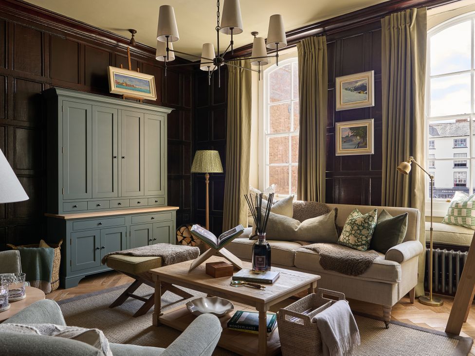 A living room with a sofa, coffee table, and paintings at Castle Corner, The Georgian House, Ludlow