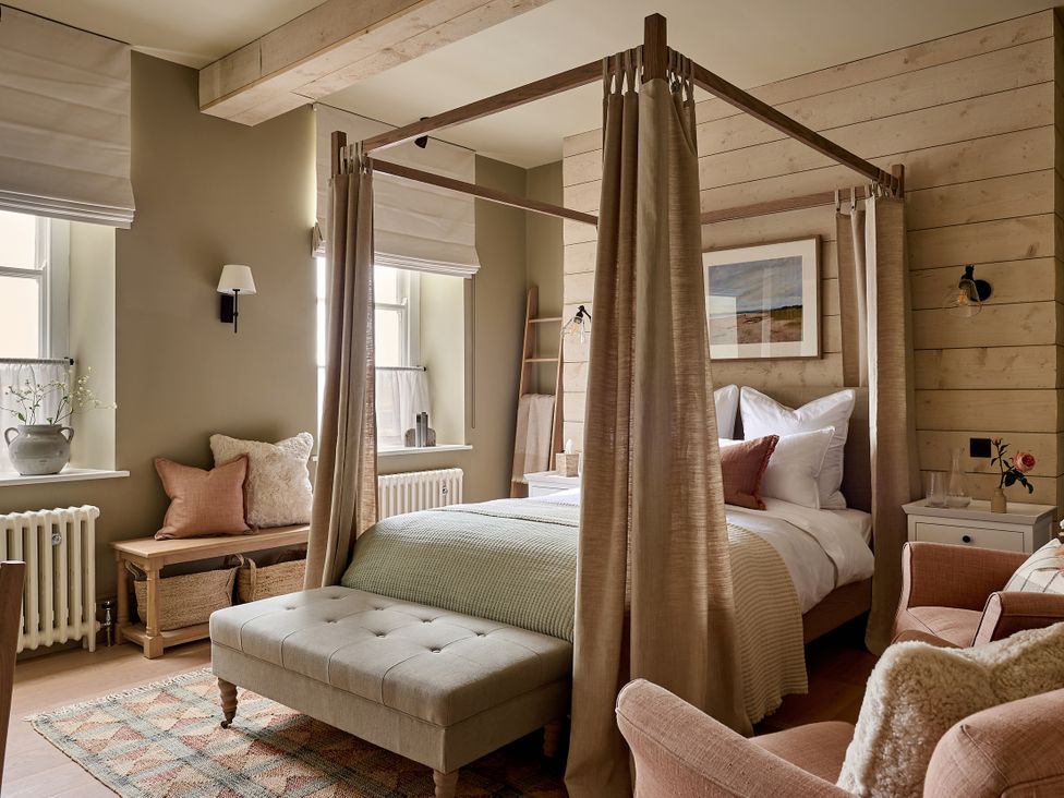 A bedroom with a canopy bed and seating area at Castle Corner, The Georgian House in Ludlow