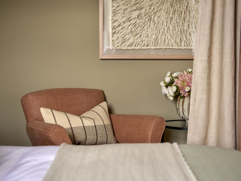 A sitting room with a chair and flower arrangement at Castle Corner, The Georgian House in Ludlow