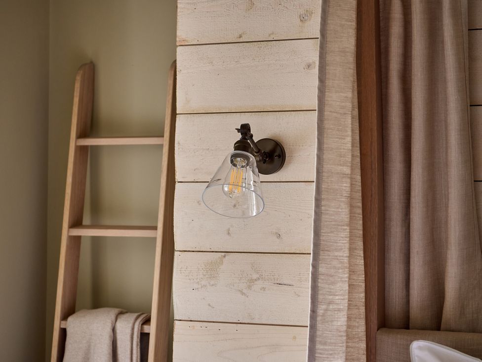 A light fixture on wood panel with a ladder and curtain at Castle Corner, The Georgian House, Ludlow
