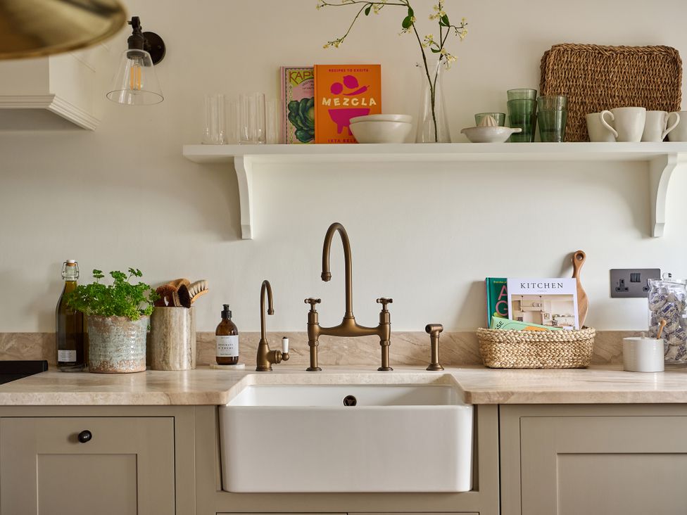 A kitchen with a sink and shelf displaying glasses and books at Stretton Hills Peaks - The Georgian House, Ludlow