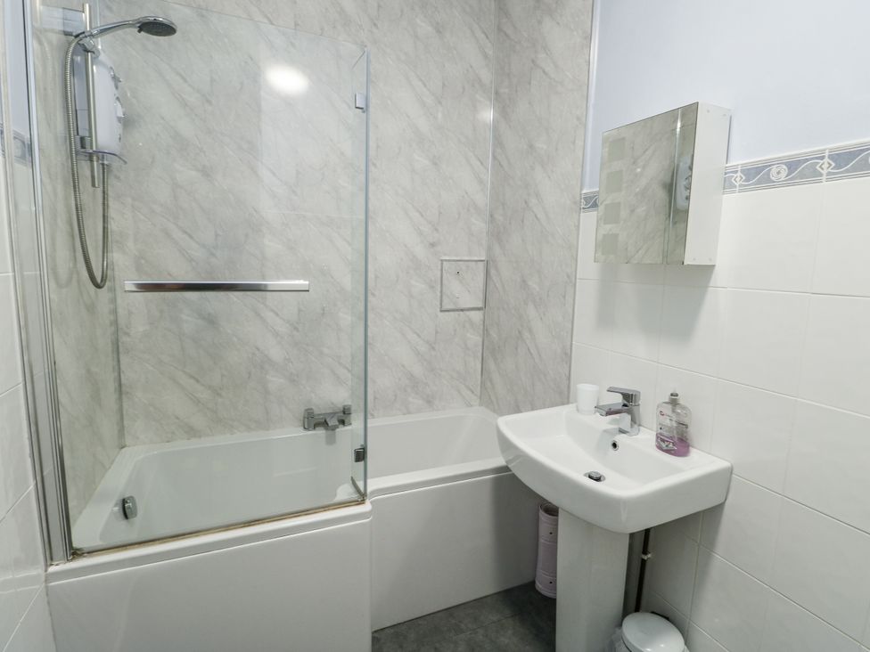 A bathroom with a bathtub shower and sink at Lady of the Lake Suite Trearddur Bay