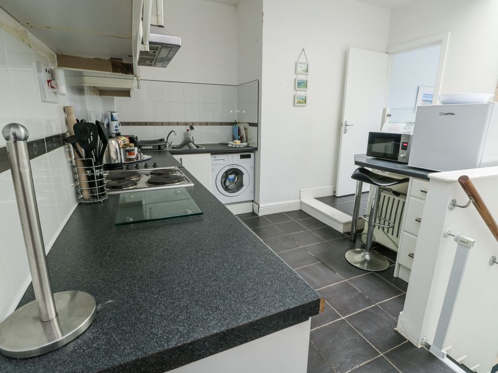 A kitchen with a stove, sink, and washing machine at Lady of the Lake Suite in Trearddur Bay