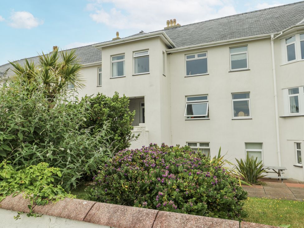 A garden view with shrubs and a building at Lady of the Lake Suite in Trearddur Bay