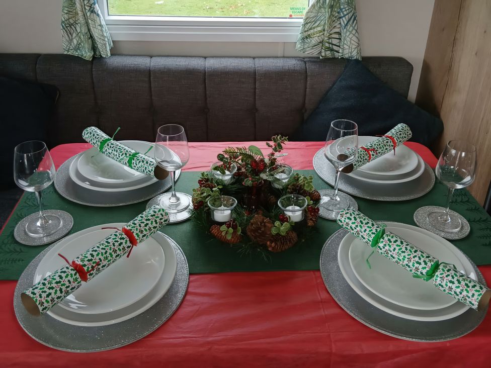 A dining table set with plates and glasses at Pines 15 in Porthcawl