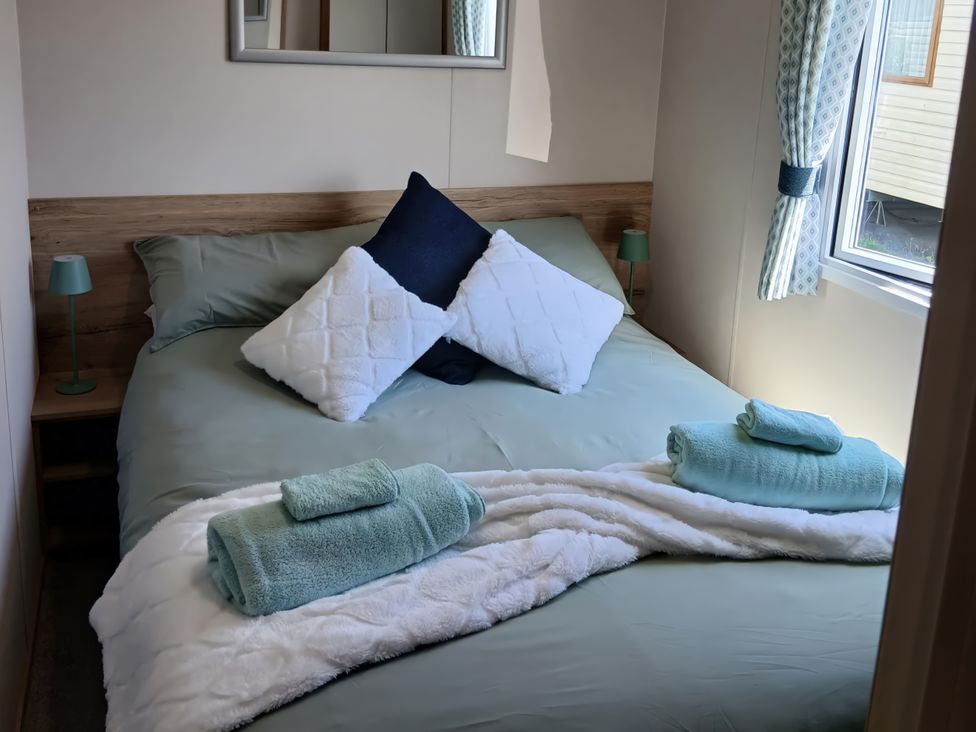 A bedroom with a bed and towels at Pines 15 in Porthcawl