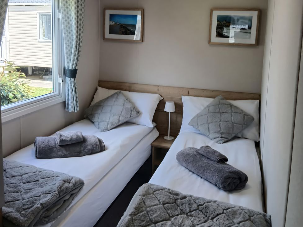 A bedroom with two beds and a window at Pines 15 in Porthcawl