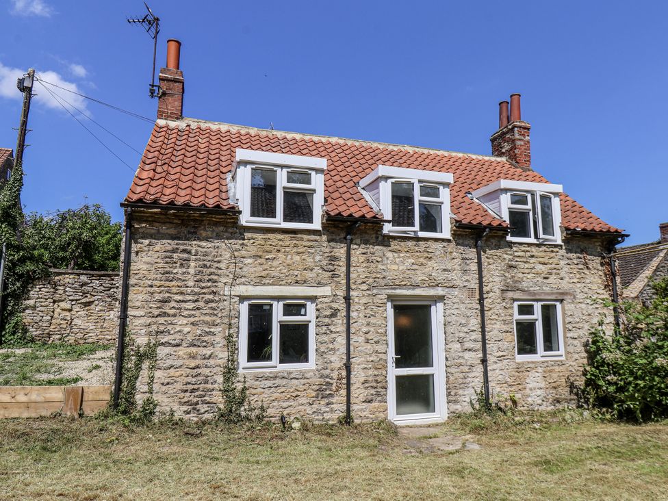 A stone house with a red roof and garden at Hemdin Cottage in Thornton Dale