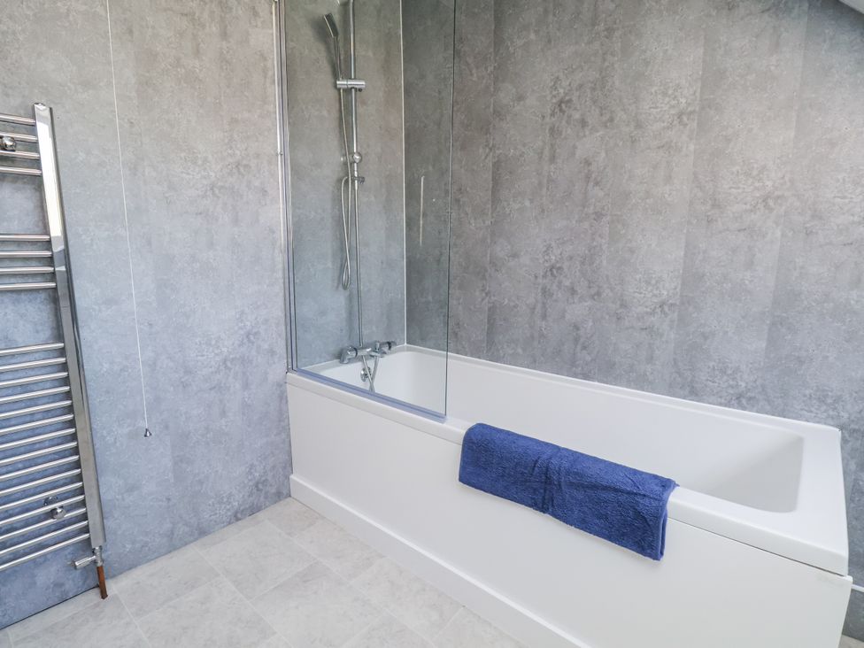 A bathroom with bathtub and towel rail at Hemdin Cottage in Thornton Dale