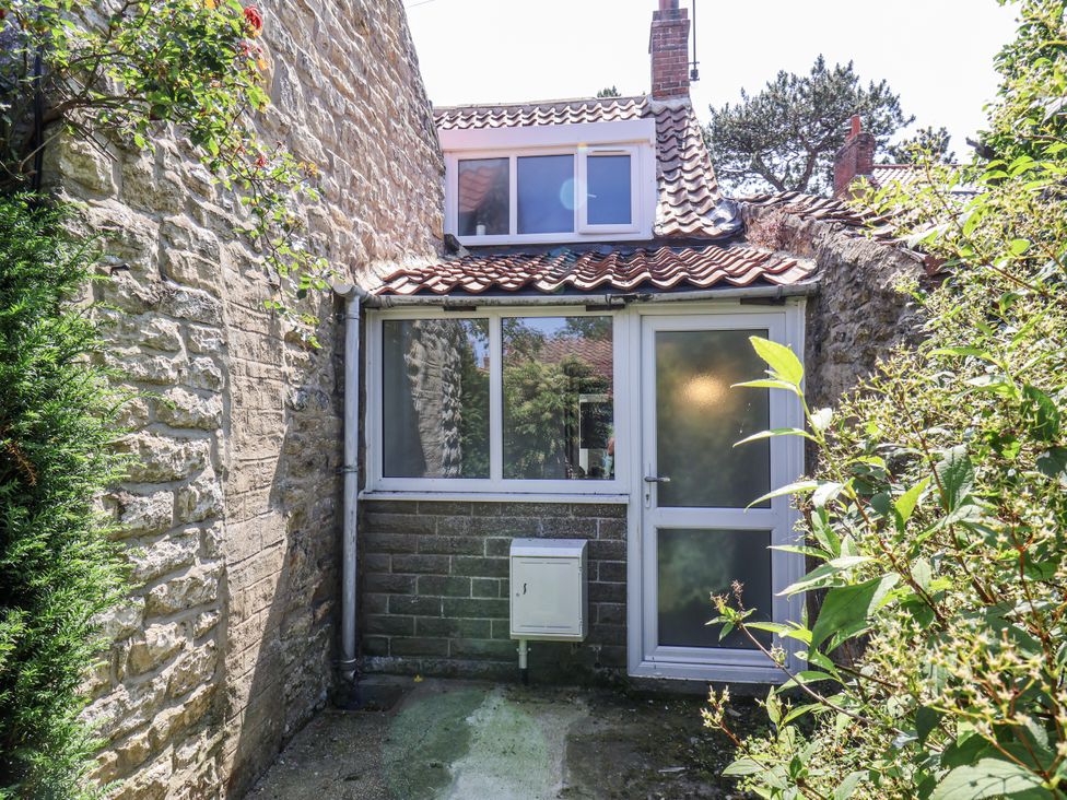 An outdoor area with a stone wall and window at Hemdin Cottage in Thornton Dale