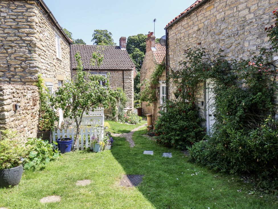 An outdoor courtyard with stone cottages and greenery at Hemdin Cottage in Thornton Dale